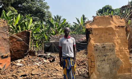 Etim Asuquo stands in front of his former home, destroyed in an attack on his village.