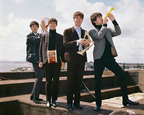 The Beatles play toy instruments together on a rooftop terrace, circa 1964