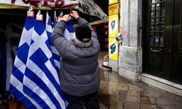 A street vendor places price tickets on Greek national flags in Athens.