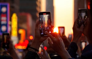 Camera phones are held aloft on 42nd Street as the city is bathed in golden light