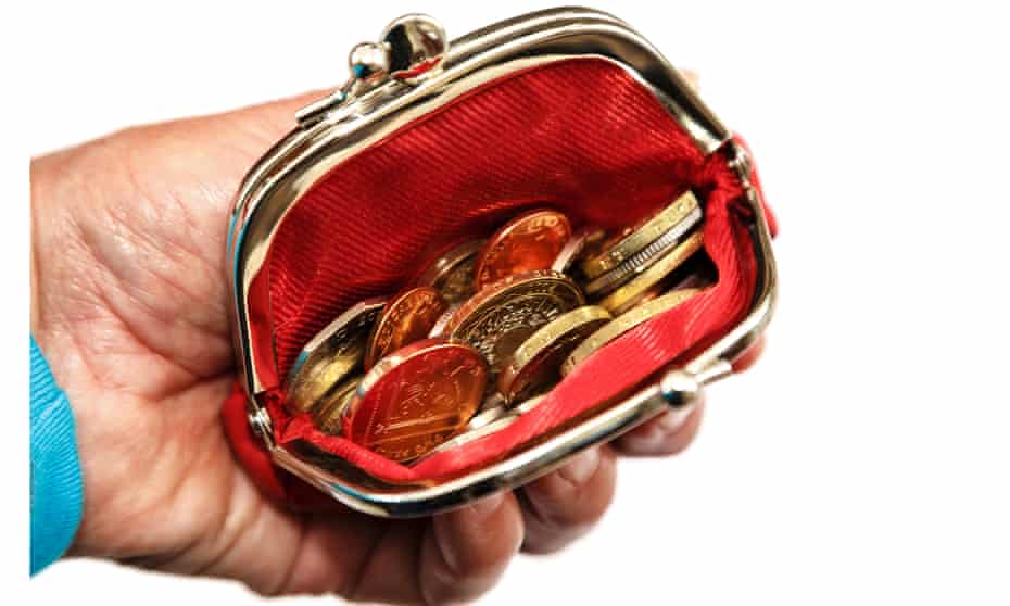 Senior pensioner's hand holding a red open coin purse with money sterling coins.