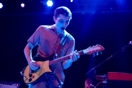 Wolfhard in a short-sleeved shirt playing the guitar