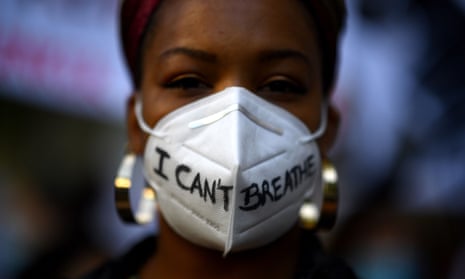 A woman wears a mask reading: I can’t breathe.