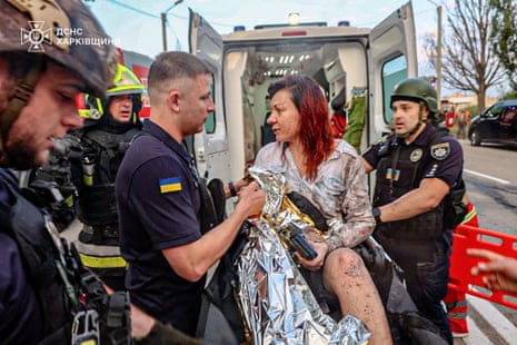 An injured woman is taken to an ambulance at the site of an attack, in Kharkiv, Ukraine.