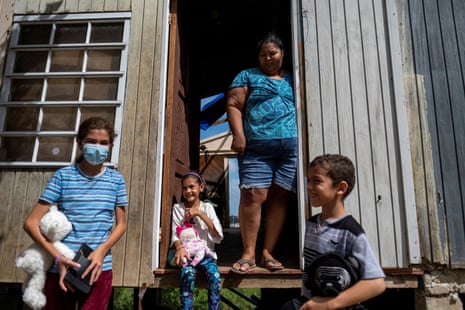 A woman and three children stand in front of their hurricane-damaged home.