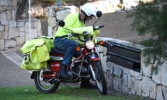 A postman on a motorbike delivers letters in Brisbane.
