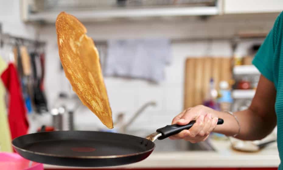 A pancake being flipped in a nonstick pan