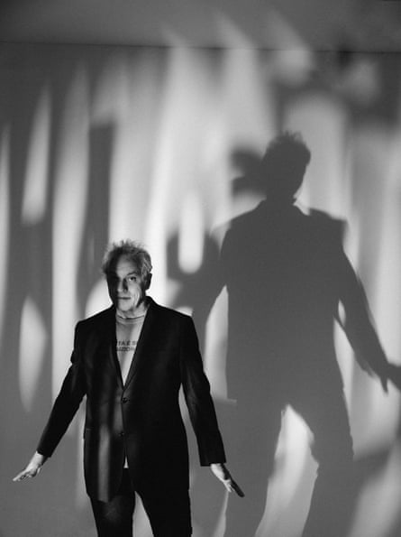 Marc Ribot stands with arms stretched downwards, covered in shadows