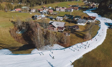 An aerial view taken on 30 December 2022 shows skiers making their way along a slope surrounded by grass in Riezlern, Austria.