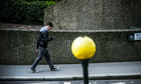 Man walking on pavement while looking at his phone.