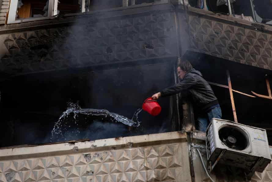 A resident uses a bucket to throw water on a neighbour’s home that caught fire after Russia shelled Saltivka, a residential area in Kharkiv.