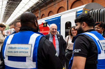Lord Hendy smiles as he speaks with Chiltern Railways staff as they stand next to a train carriage