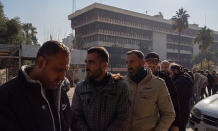Bearded men queue to get temporary ID documents at a settlement centre run by HTS.