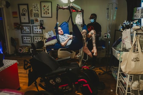 A man in a lift with a nurse watching on in the background.