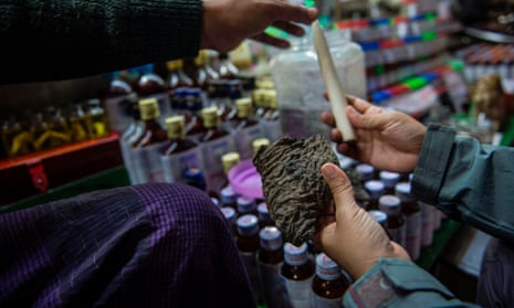 A vendor tries to sell a chunk of dried elephant skin and an ivory tusk at a traditional medicine shop in Myanmar.
