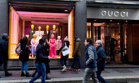 People walk past the window of Gucci on via Montenapoleone in Milan.