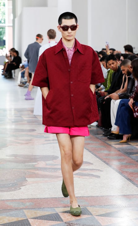 A model in a burgundy shirt and pink short shorts