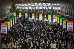 Commuters, mostly wearing face masks, walk through Shinagawa train station in Tokyo on Wednesday.