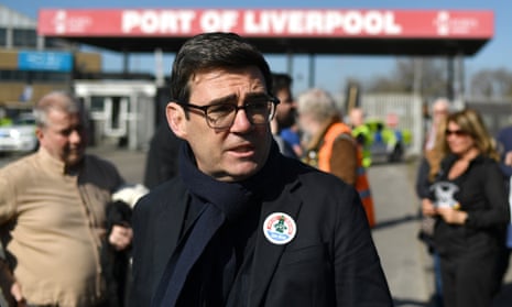 Andy Burnham stands in front of sign reading Port of Liverpool. Wears badge supporting union
