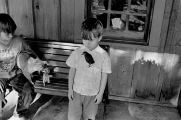 Isaac stands with an adopted starling on his shirt, while his brother Noah holds a cat