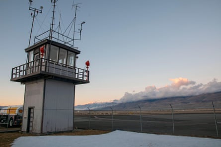 tower over chain link fence; mountains in the distance