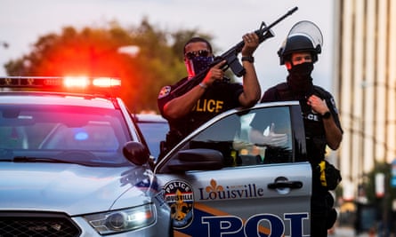 Police officers stand guard as demonstrators march during a peaceful protest in Louisville, Kentucky on 26 September.