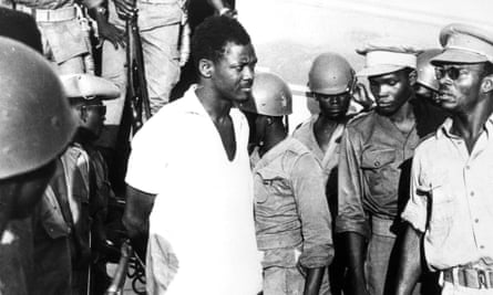 Patrice Lumumba surrounded by armed guards on airport tarmac