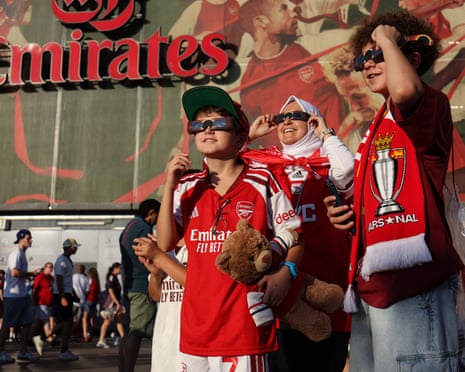 Arsenal fans watch the solar eclipse ahead of the pre-season friendly match between Arsenal and Como at Emirates Stadium in London.