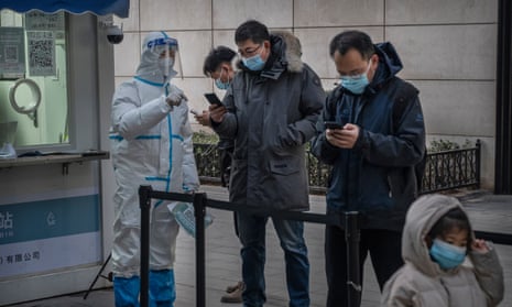 A health worker wears protective clothing as he helps people register for a nucleic acid test for Covid-19 at a testing site in Beijing, China.