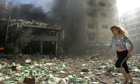 A woman runs past a destoyed building in Beirut, Lebanon, after it was attacked by Israel.