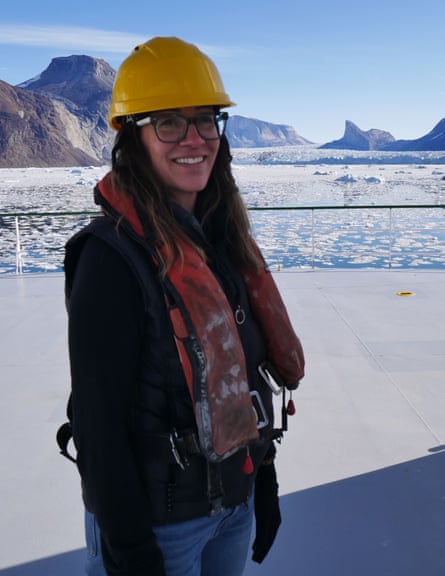 Prof Ginny Catania in a yellow hard hat stood near a glacier