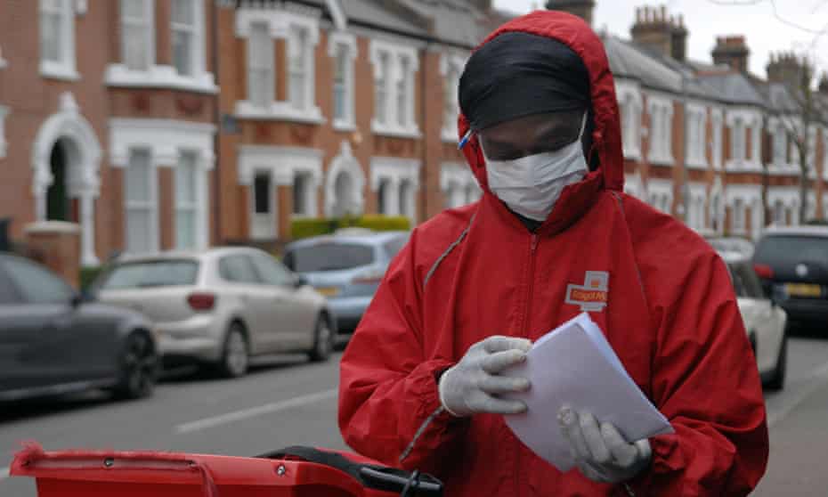 A Royal Mail postman wears a face mask and protective gloves whilst delivering mail in Wandsworth, London.