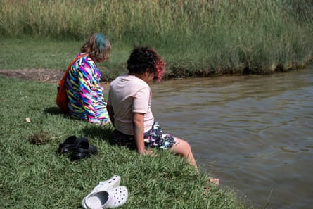 two young children sitting by the lake