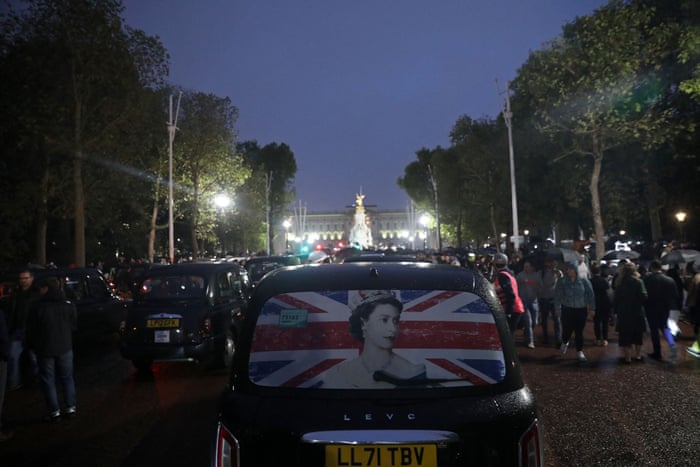 A London taxi displaying a photograph of the Queen amid crowds of well-wishers on The Mall.