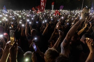 Crowds of people hold up mobile phone torches