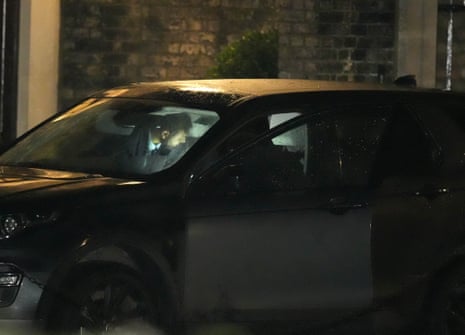 A police officer looking inside a car with a torch.