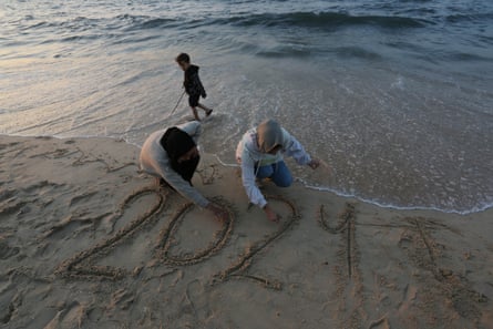 Gazans write a sunset new year message in the sand at Deir al-Balah beach in Gaza on 31 December.