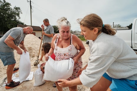 Lisa Quiggle hands a sandbag to Samantha Riechers amid hurricane preparations in Alabama