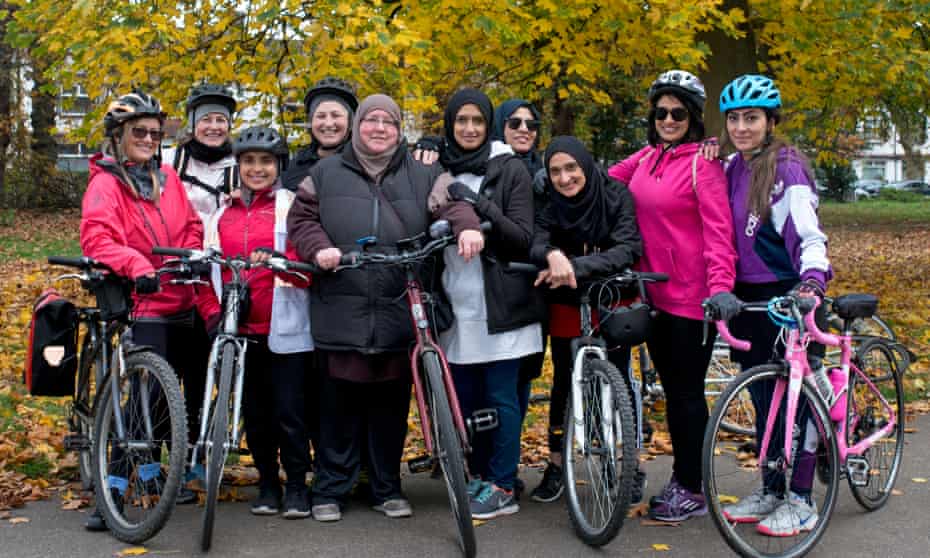 Joy Riders, a group of women only cyclists, standing together, a few of them with bikes, in a park