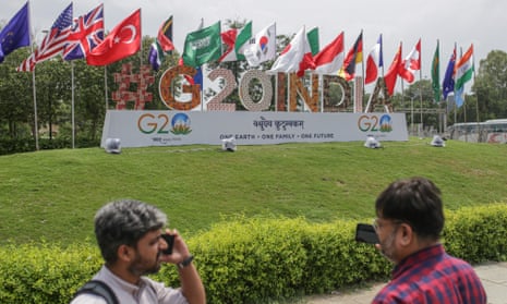 Flags of the G20 member nations fly above a G20 India sign on a small mound