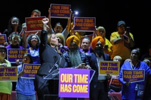 Letitia James on stage with a crowd holding signs that say ‘Our time has come’