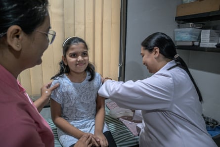 A doctor gives a girl a vaccine injection in her arm at a clinic