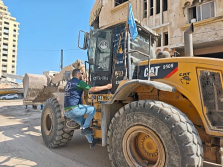 Man mounts a yellow bulldozer with a WFP flag
