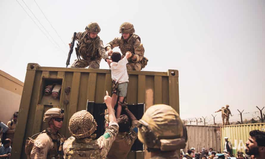 UK and Turkish coalition forces and US Marines assist a child during an evacuation at Kabul airport in August