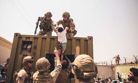 UK and Turkish coalition forces and US Marines assist a child during an evacuation at Kabul airport in August