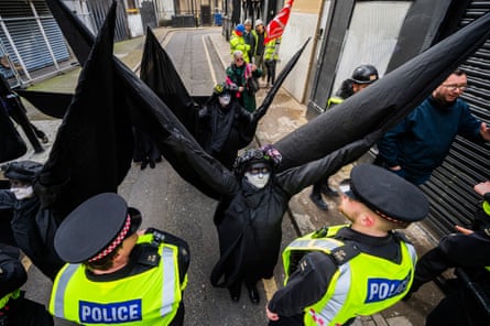Police face protesters in flamboyant black costumes in a street