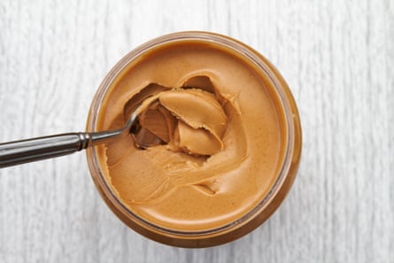 The top view of a jar of peanut butter with a spoon.