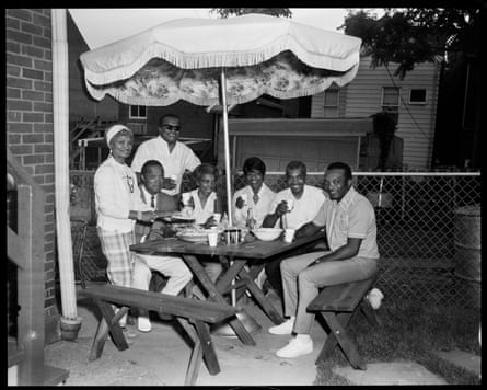 Members of the Harper family sit at a picnic table under a patio umbrella