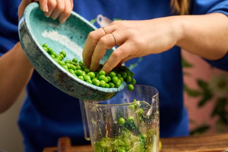 Chef pouring frozen peas into a blender to add to guacamole