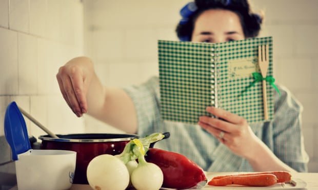 Woman reading recipe book and cooking.